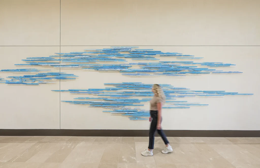 28-TIAA-Art-Package-Portfolio Woman admires large-scale art in office corridor.