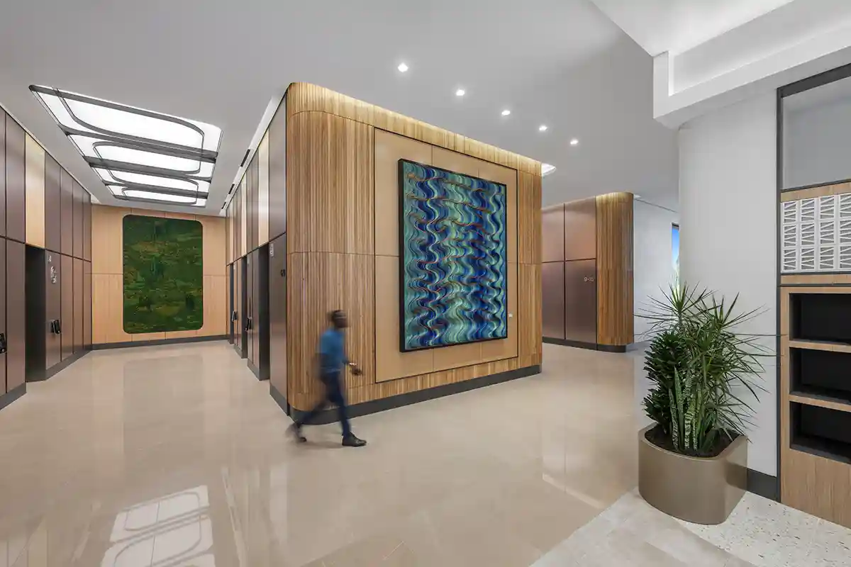 Man walking by 500 lb. statement artwork hanging on wall of office lobby.