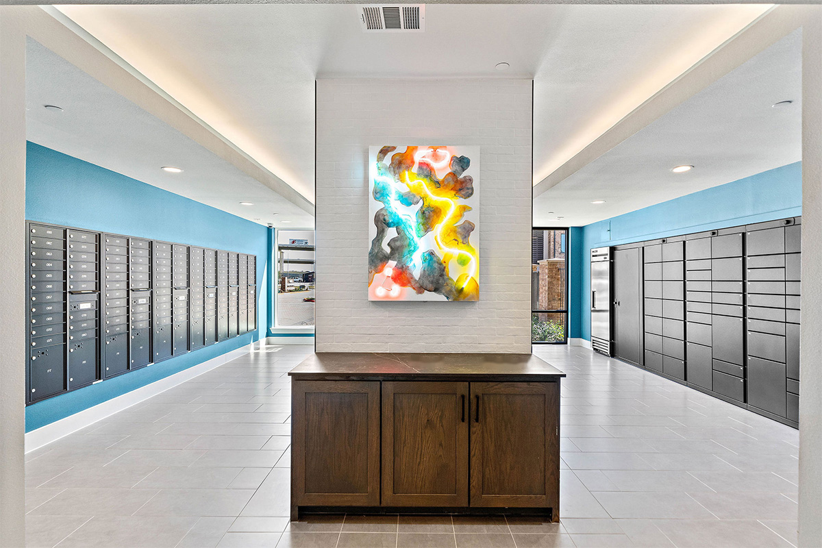A brightly colored neon painting is displayed in a large mailroom of a multifamily residence.