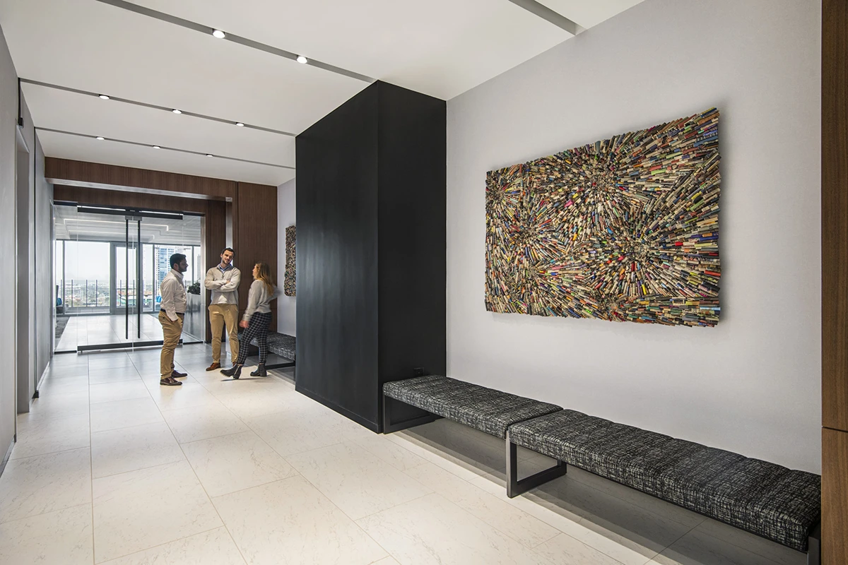 Grey office hallway with multi-colored, mixed-media artwork on the wall.