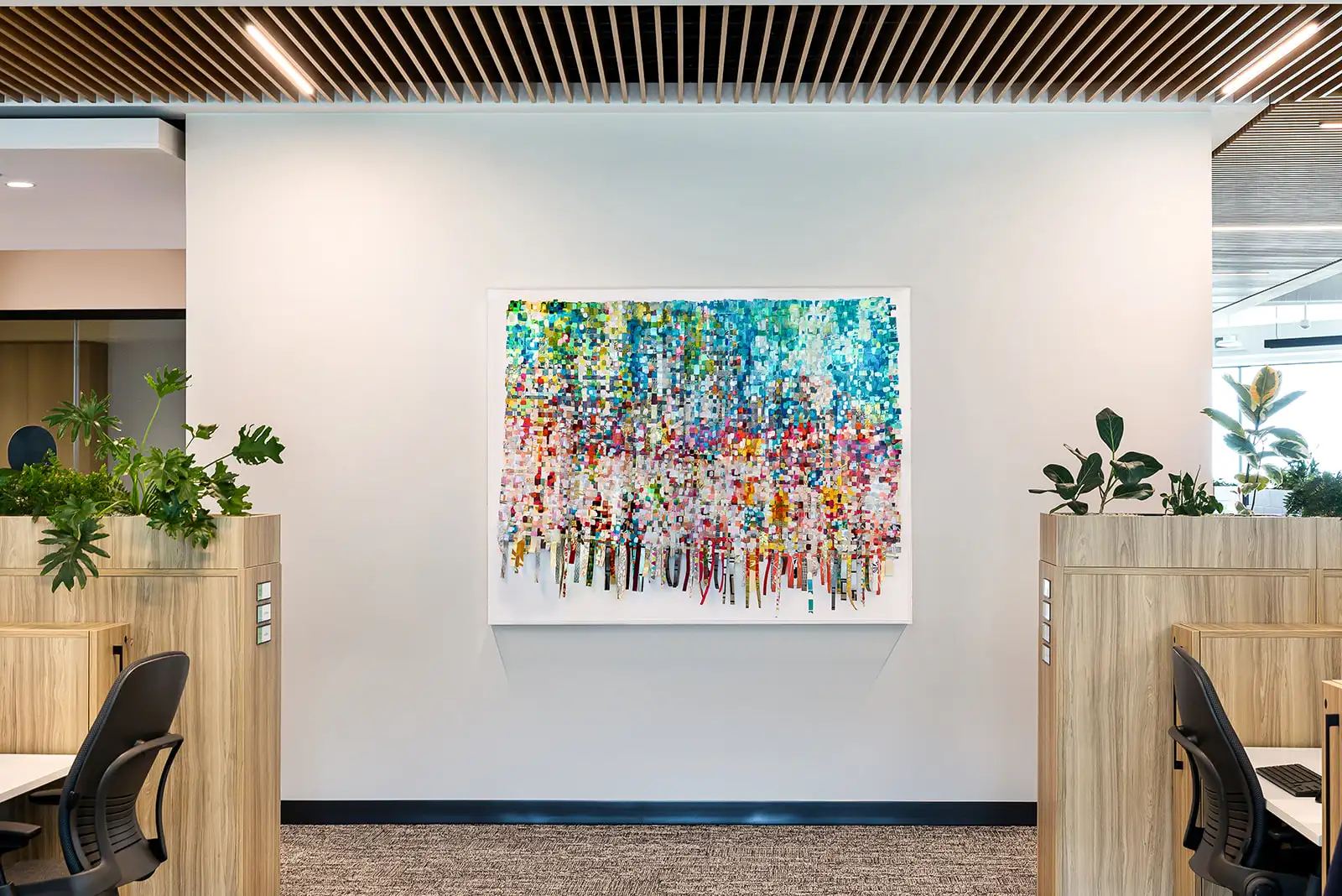 A cream and brown office corridor with a vibrant, multicolored abstract painting hanging on the wall.