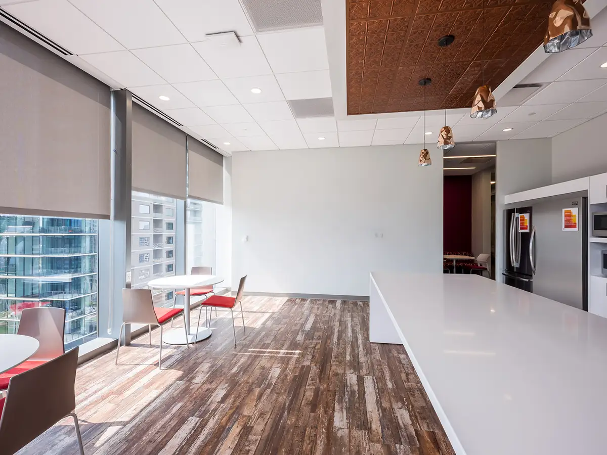 An office breakroom with a bare, white wall and a view overlooking the city.