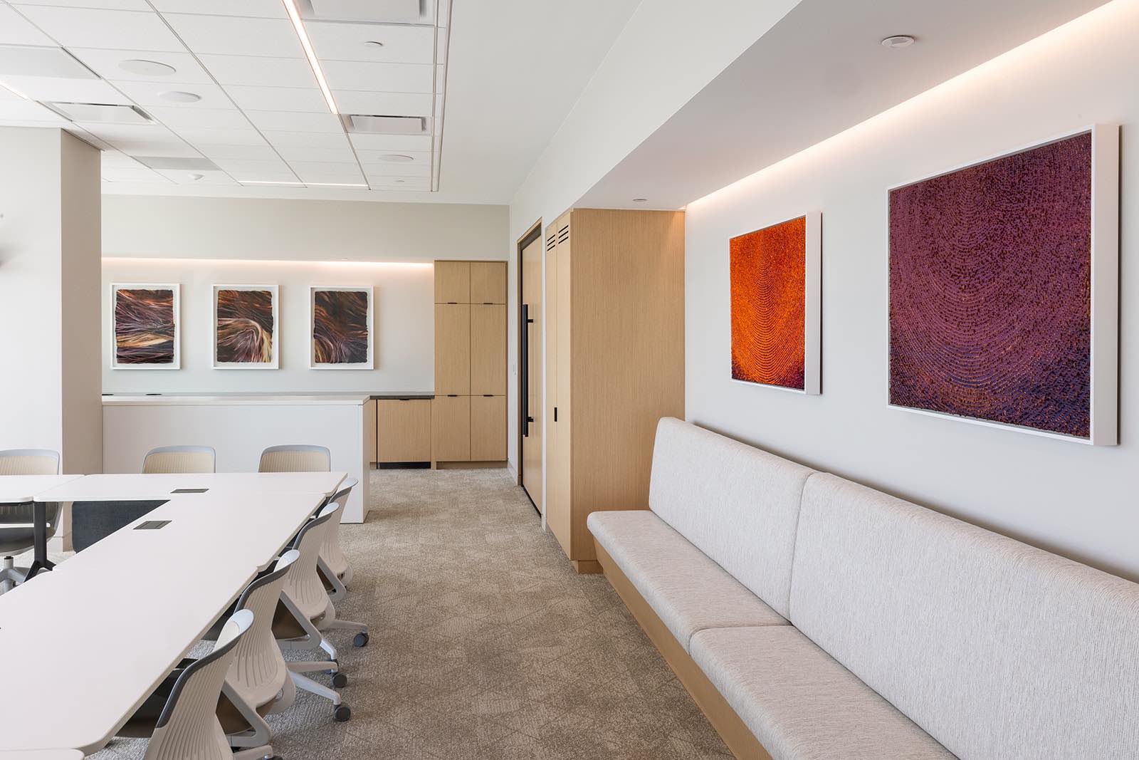 A beige and cream conference room with colorful framed art on the walls.