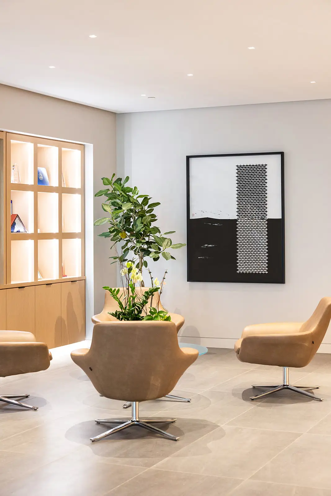 A beige and brown office lobby waiting area with a framed abstract painting on the wall.