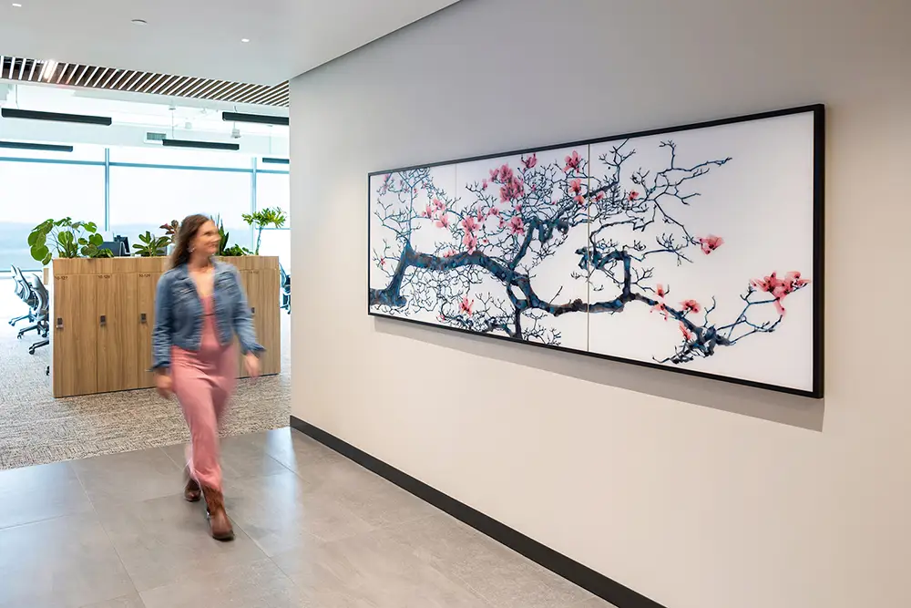 A woman looks at an original work of art as she walks by in an office corridor.