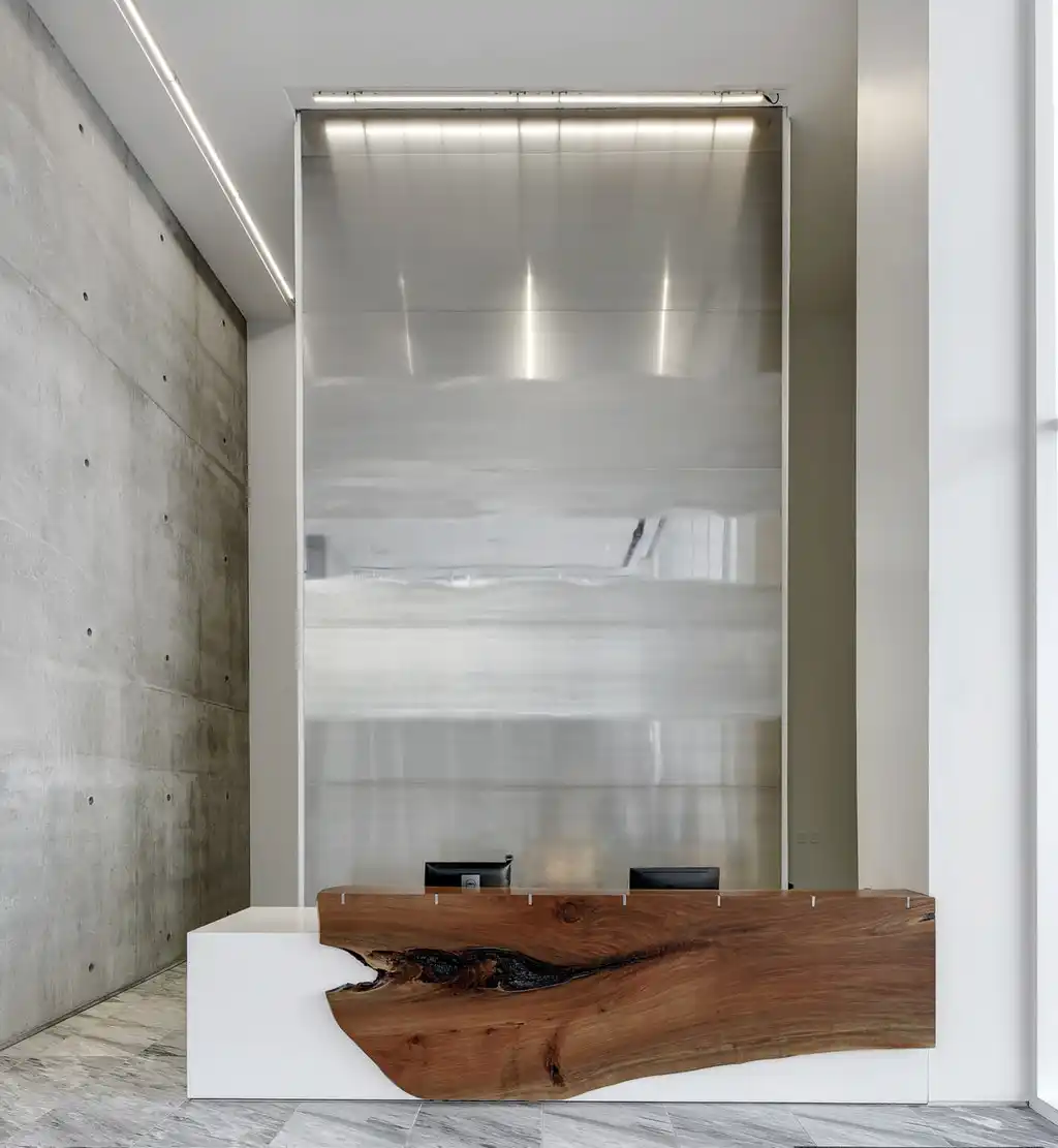 A brushed aluminum art installation behind the reception desk in a luxury apartment tower lobby.