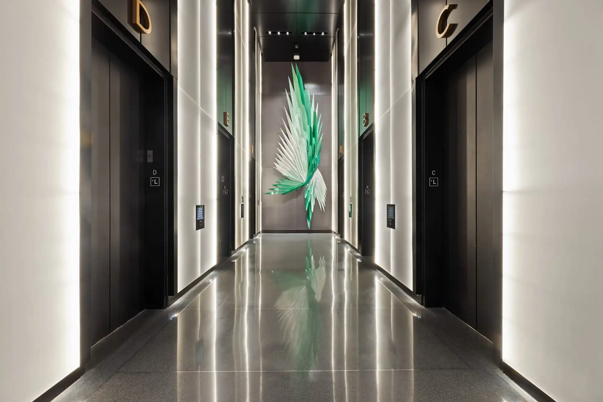 Large green and white geometric wall sculpture hangs in an elevator lobby.